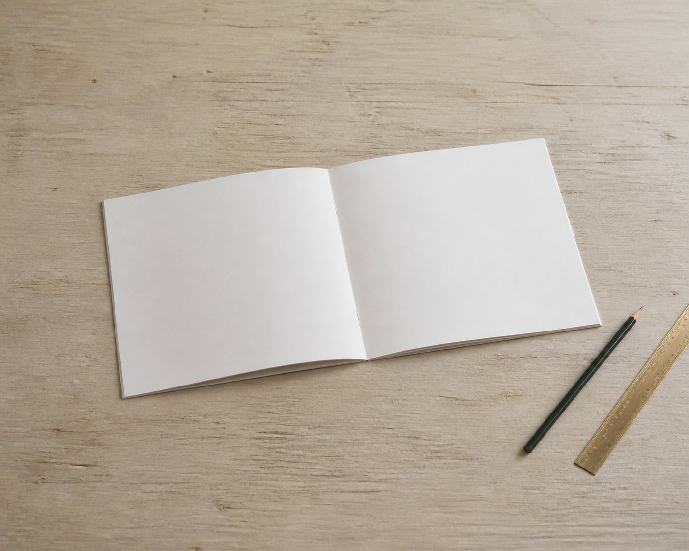 机に置かれた白紙の中綴じ冊子と定規と鉛筆